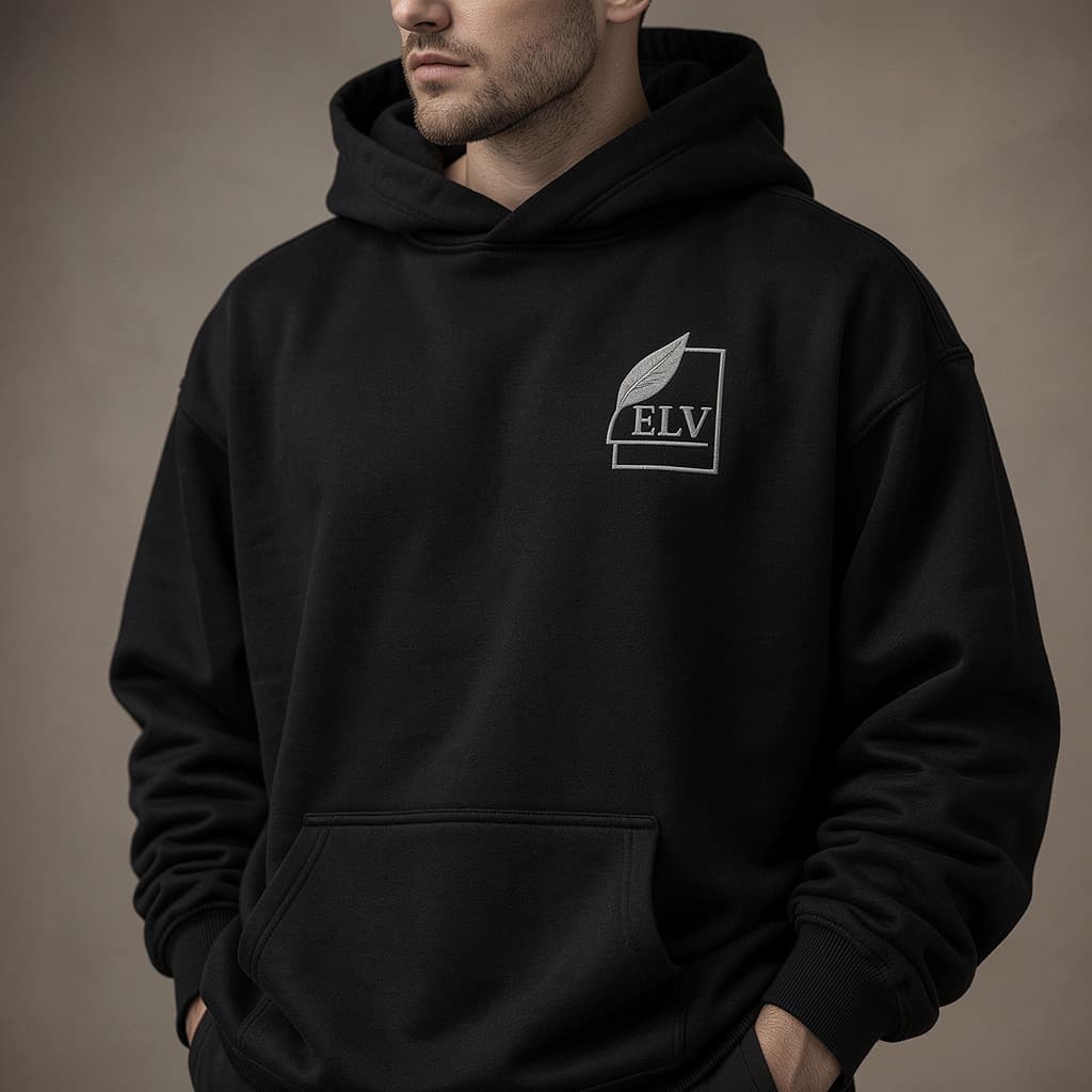 Person wearing a black hoodie with an 'ELV' logo on a brown background
