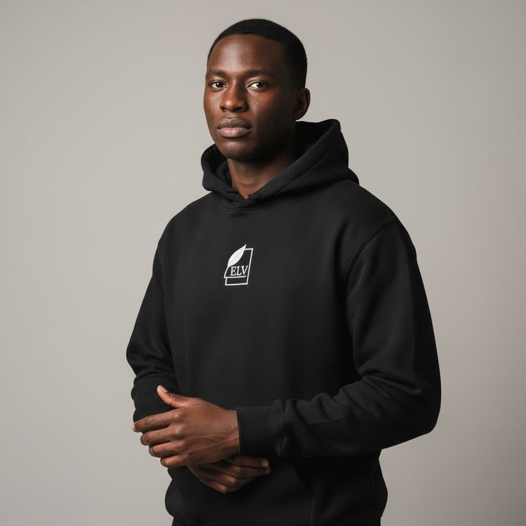 Man wearing a black hoodie with a logo on a gray background