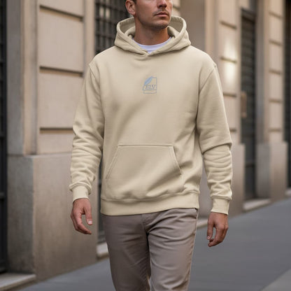 Man wearing a beige hoodie with a logo walking on a street.